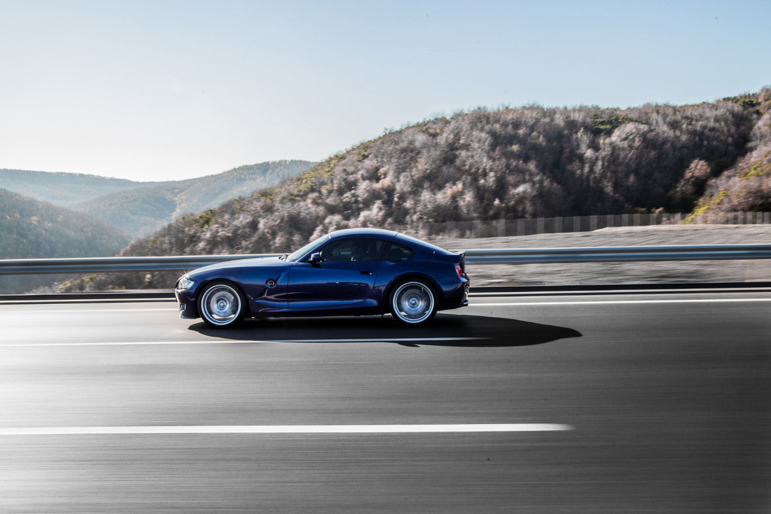 Sedan driving a highway between mountains
