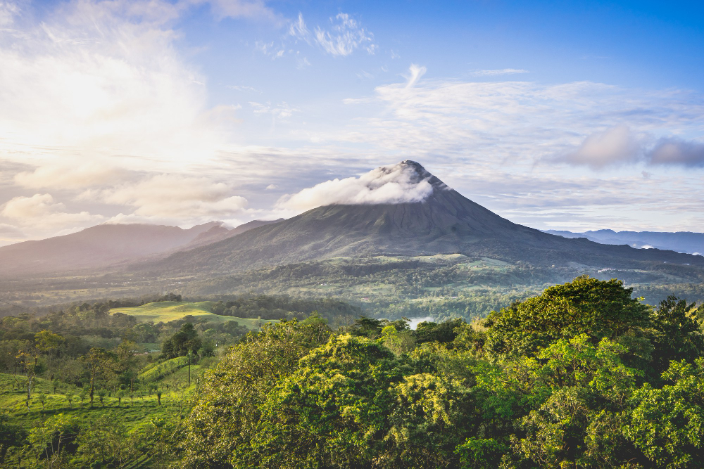 Volcano wrapped in cloud above a tropical landscape
