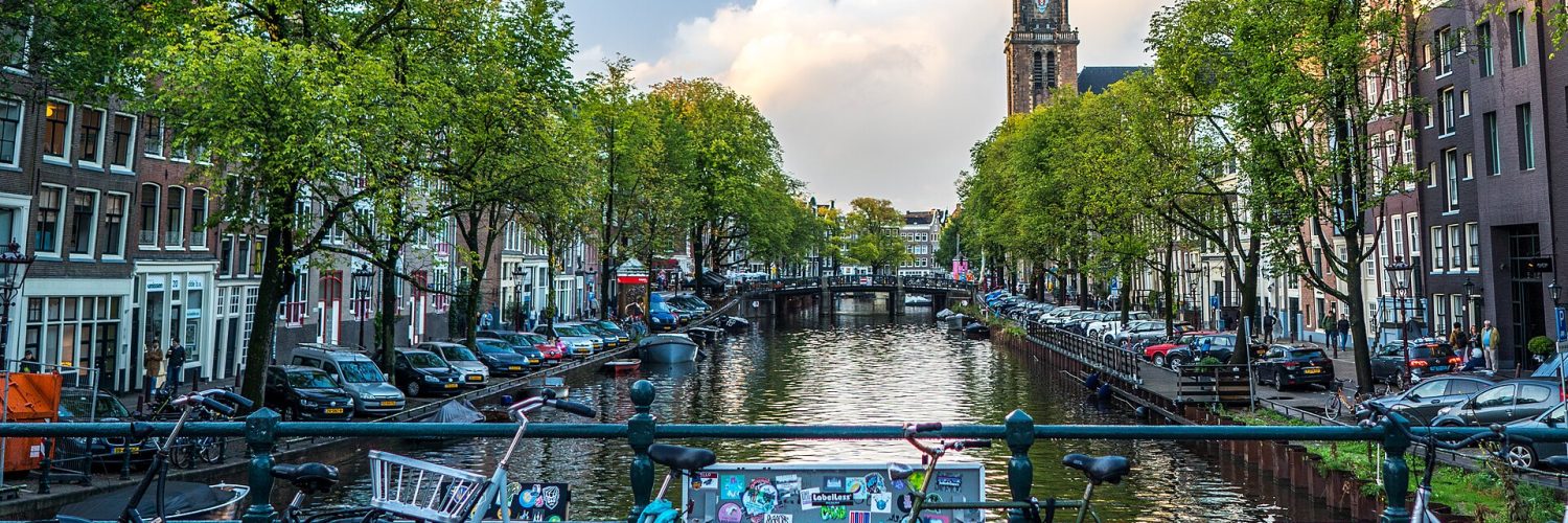 Rental bicycles locked along a canal bridge railing in central Amsterdam