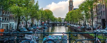 Rental bicycles locked along a canal bridge railing in central Amsterdam