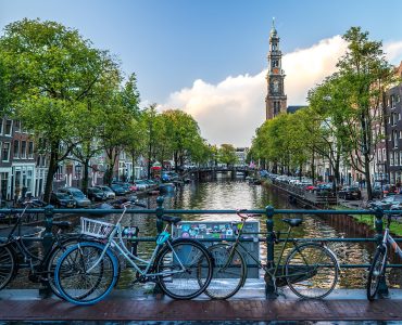 Rental bicycles locked along a canal bridge railing in central Amsterdam