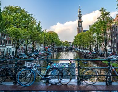 Rental bicycles locked along a canal bridge railing in central Amsterdam