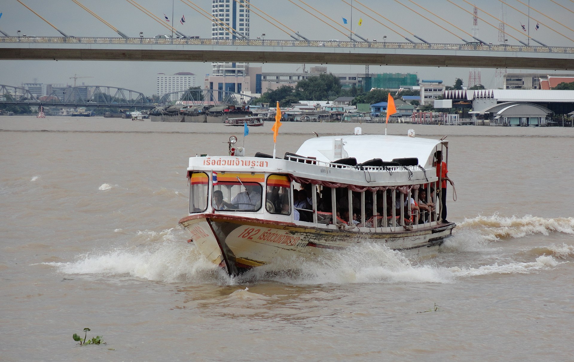 A Chao Phraya Express Boat pulling into a river pier in Bangkok