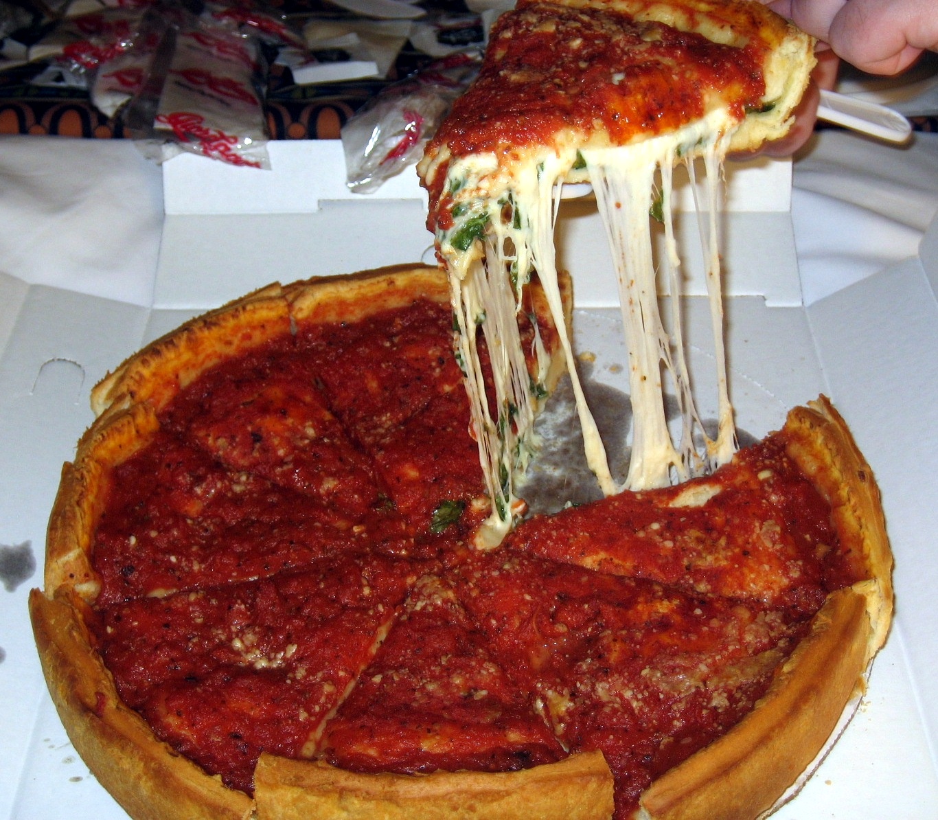 A slice of Chicago deep dish pizza being lifted from the pan
