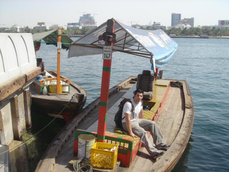 A wooden abra water taxi crossing Dubai Creek with passengers aboard