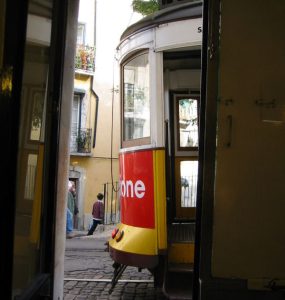A yellow tram climbing through the Alfama district of Lisbon