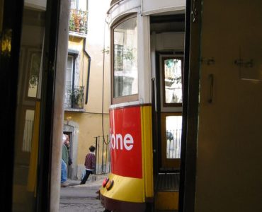 A yellow tram climbing through the Alfama district of Lisbon