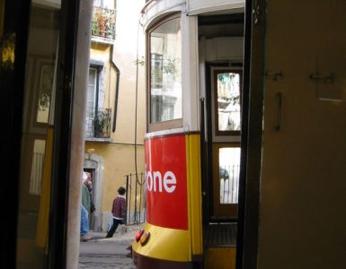 A yellow tram climbing through the Alfama district of Lisbon