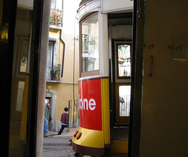 A yellow tram climbing through the Alfama district of Lisbon