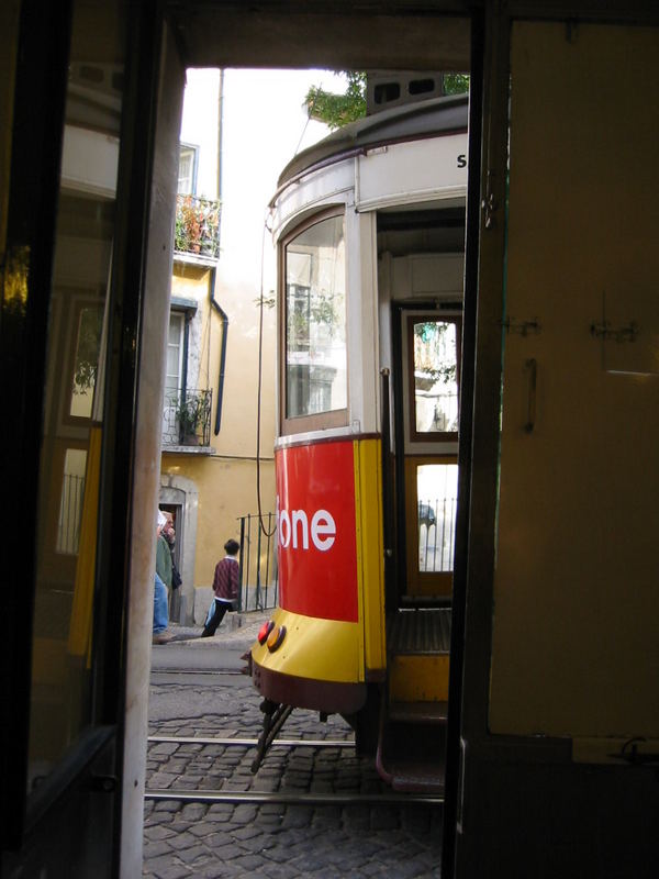 A yellow tram climbing through the Alfama district of Lisbon