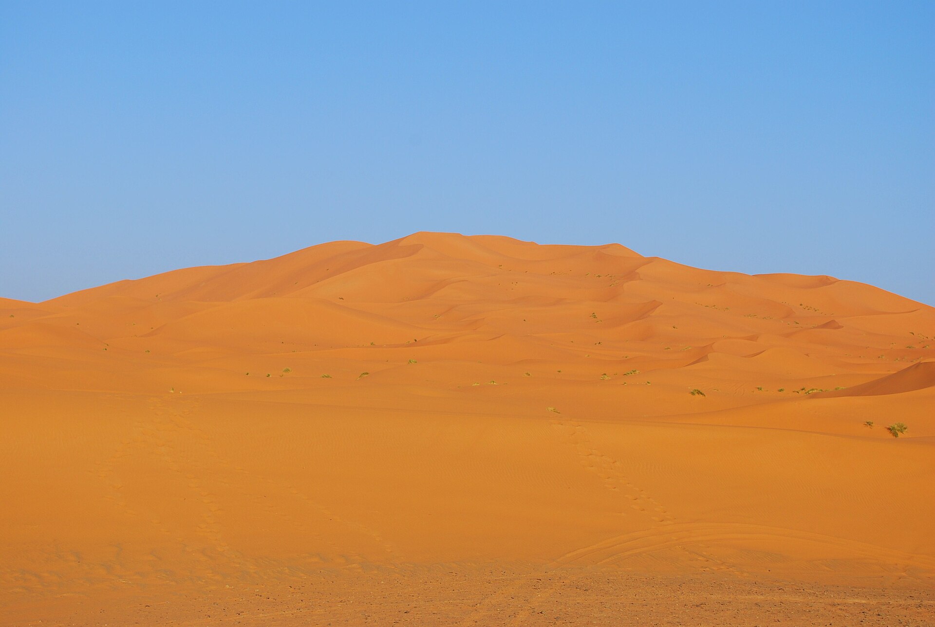 The orange sand dunes of Erg Chebbi rising behind the village of Merzouga
