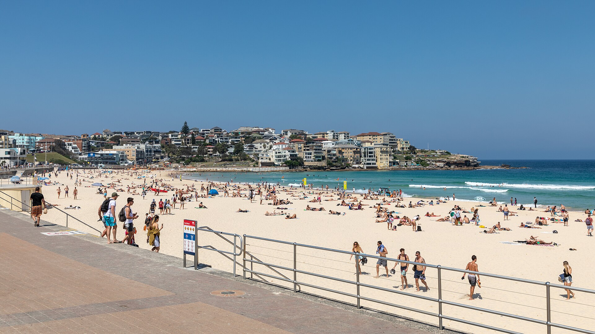 Surfers and swimmers on Bondi Beach in Sydney on a clear day