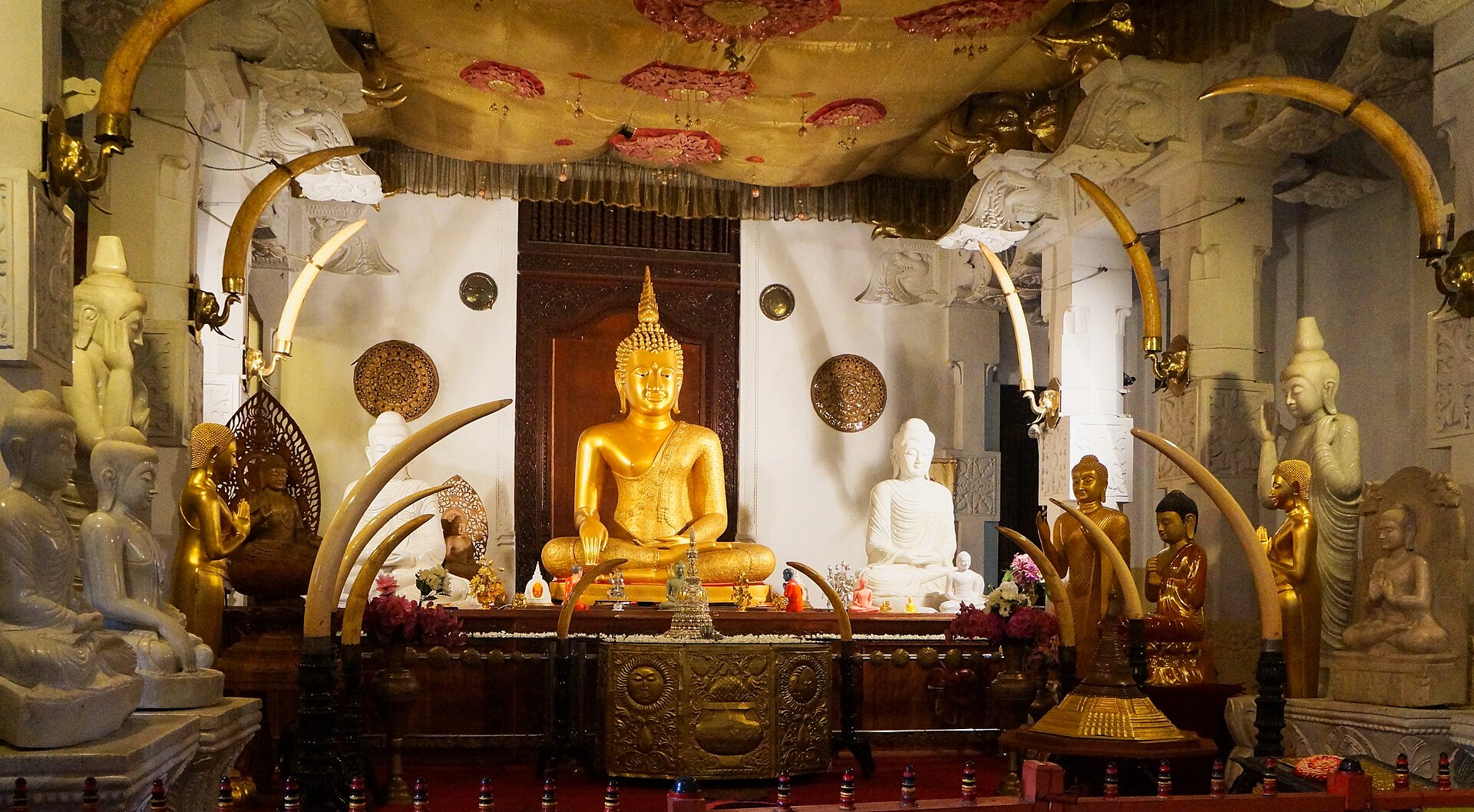 Rows of seated Buddha statues at the Temple of the Sacred Tooth Relic in Kandy, Sri Lanka