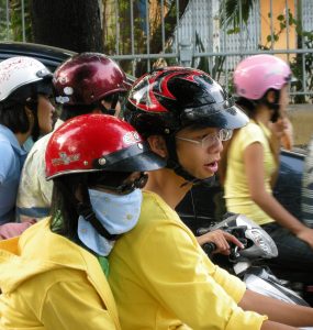 Dense scooter traffic on a street in Ho Chi Minh City